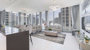 A modern living room with a sofa set, a coffee table, and a large window offering a view of high-rise buildings.