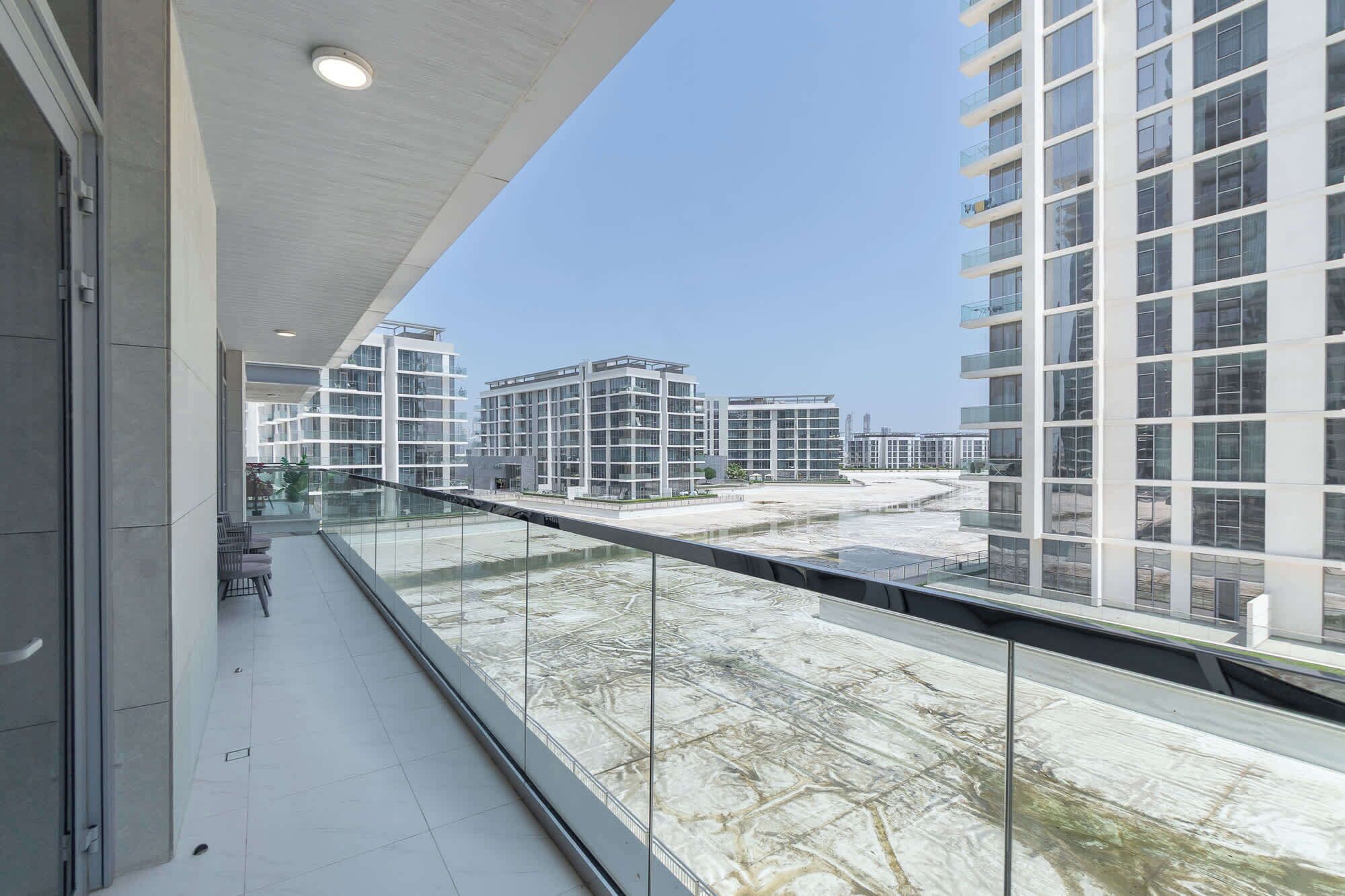 Un edificio moderno con balcón de vidrio que da a una zona en construcción.