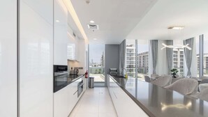 A modern kitchen with a central island, a dining area with a view, and a large window.