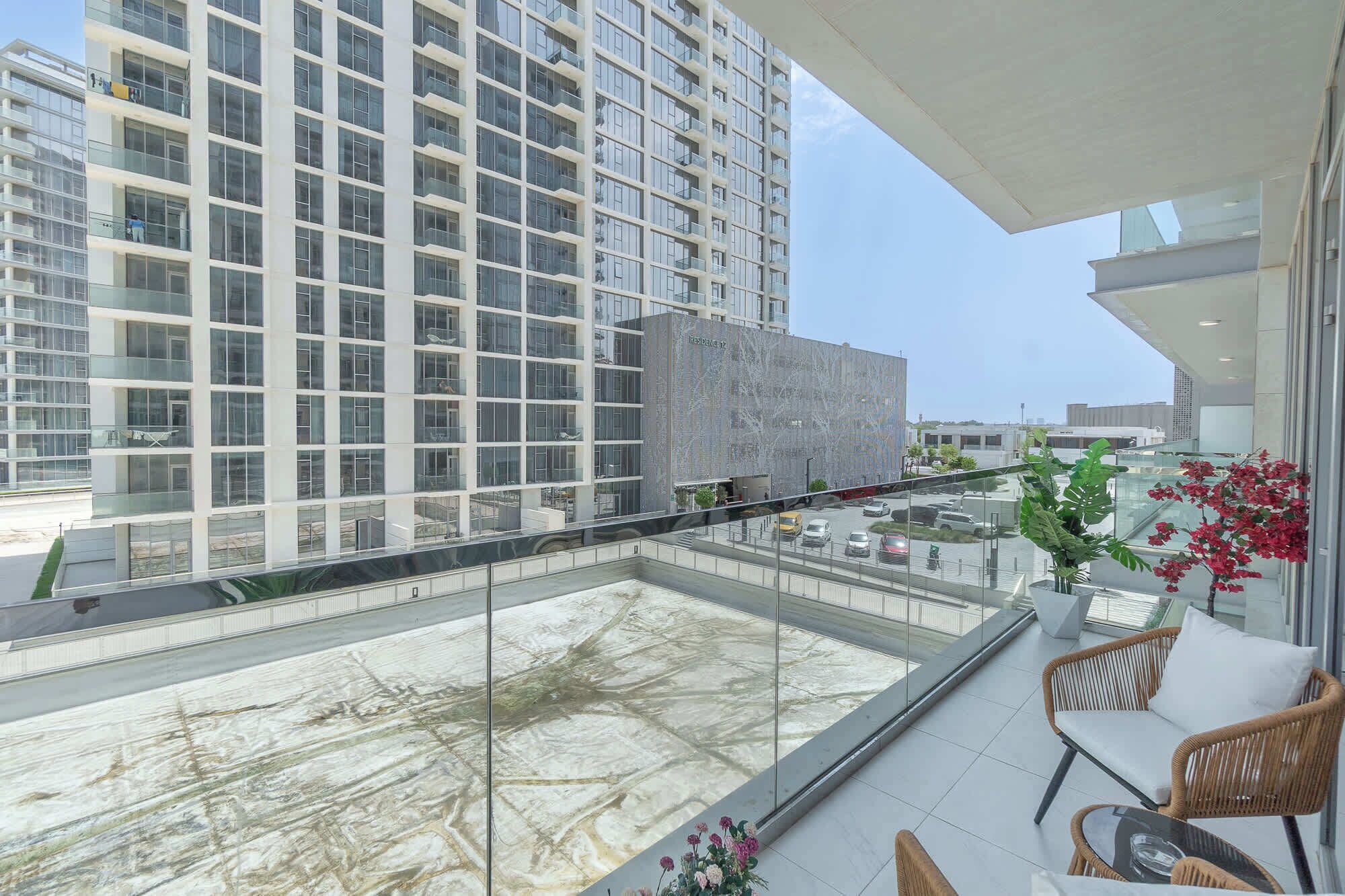 Un edificio moderno con fachada de vidrio y una terraza en la azotea con mobiliario exterior.