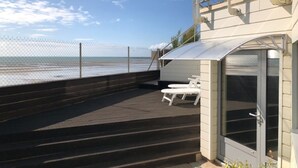 A deck with a view of the ocean, a covered seating area, and a door leading to a covered space. - 1-bedroom Apartment With View of Private Beach (Agon-Coutainville)