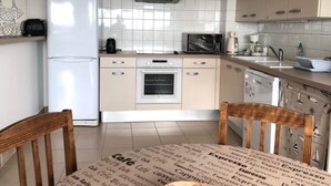 A modern kitchen with white cabinets, a built-in oven, a microwave, and a coffee maker. - 1-bedroom Apartment With View of Private Beach (Agon-Coutainville)