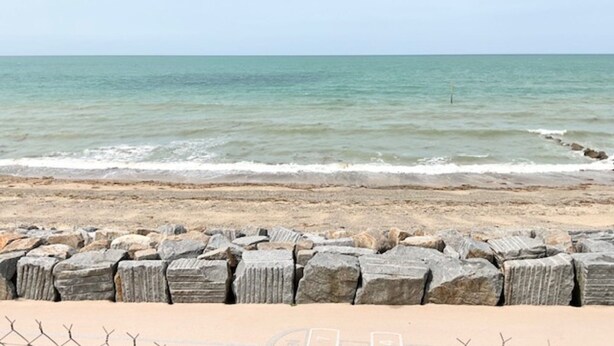 A beach with a stone breakwater in the foreground and calm sea waves. - 1-bedroom Apartment With View of Private Beach (Agon-Coutainville)
