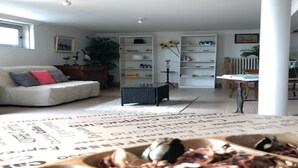 A living room with a white sofa, a coffee table, and a bookshelf. - 1-bedroom Apartment With View of Private Beach (Agon-Coutainville)