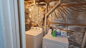 A laundry room with two washing machines, a water heater, and visible plumbing.