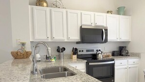 A modern kitchen with white cabinets, a granite countertop, stainless steel appliances, and a built-in microwave. - Bright 3B w Pool Close to Disney Encantada 8545 (Kissimmee)