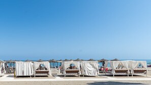 A beach with rows of white canopies over beds, providing shade.