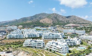Zona residencial con edificios modernos, una montaña al fondo y cielo despejado.