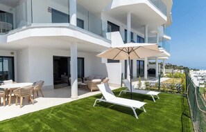 A modern building with a balcony, outdoor seating, and a view of the city. - Casa Lucia Mediterranean Garden Suite Higueron (Fuengirola)