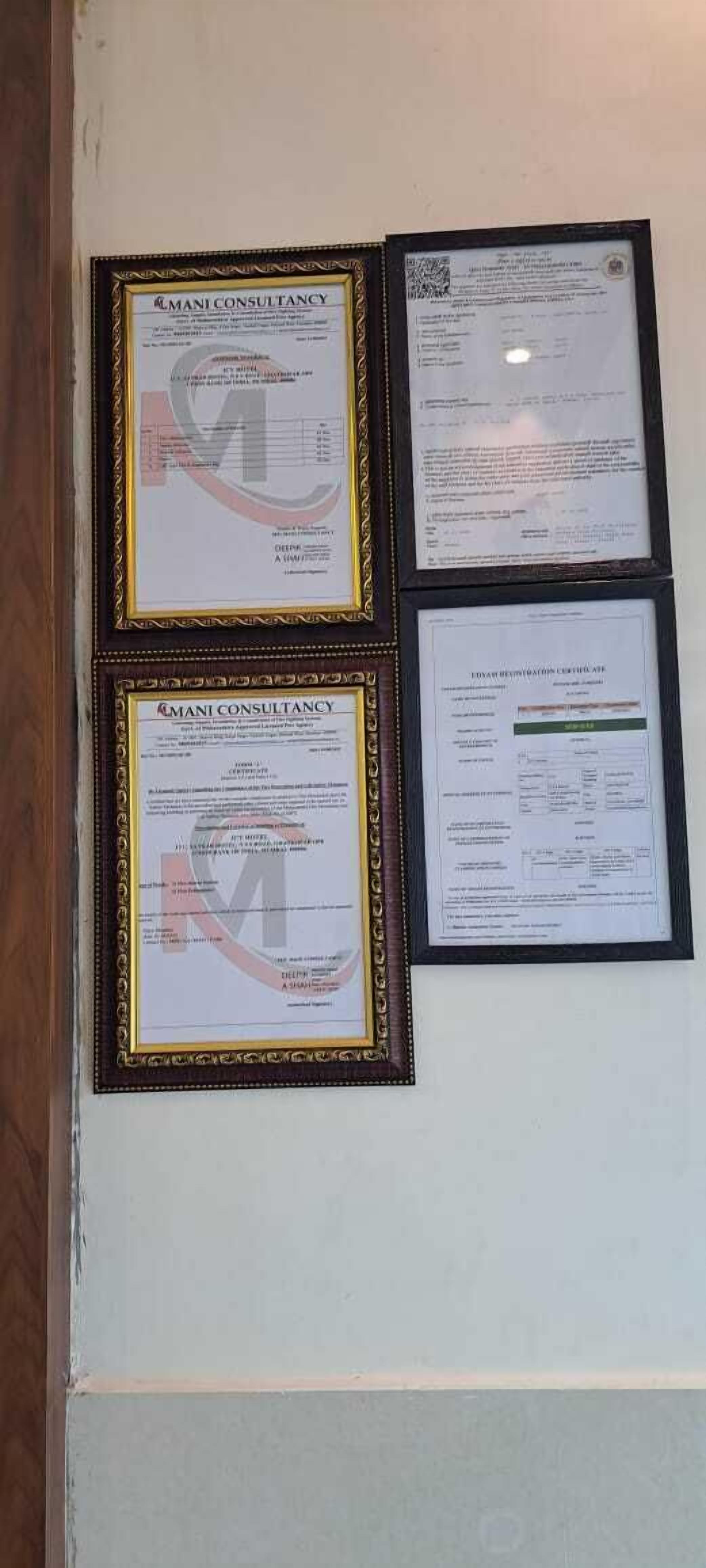 Tres documents emmarcats a la paret, incloent un certificat de Mani Consultancy.