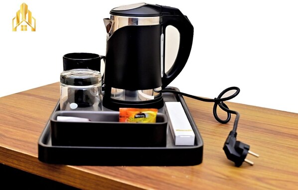 Una cafetera con una bandeja, un vaso y un paquete de azúcar sobre una mesa de madera.