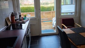 Une cuisine compacte avec un coin repas, une porte-fenêtre coulissante donnant sur une terrasse et une vue sur un quartier résidentiel.
