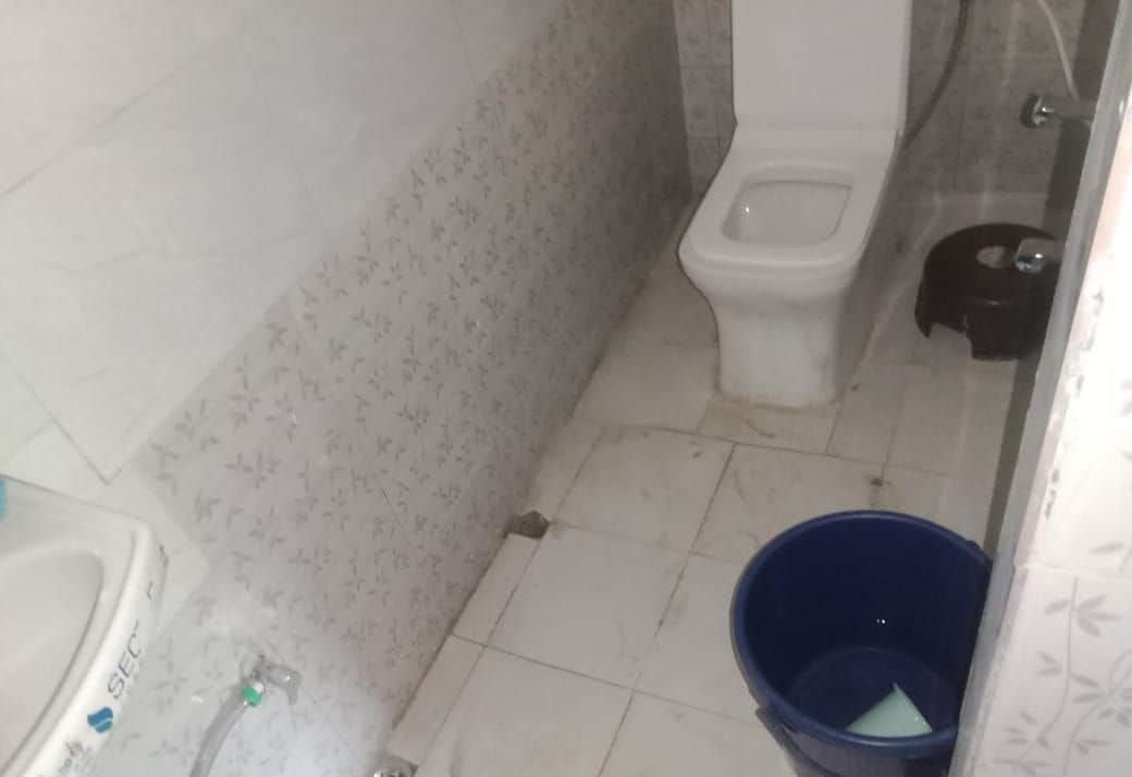 A small bathroom with a toilet, a sink, and a blue bucket.
