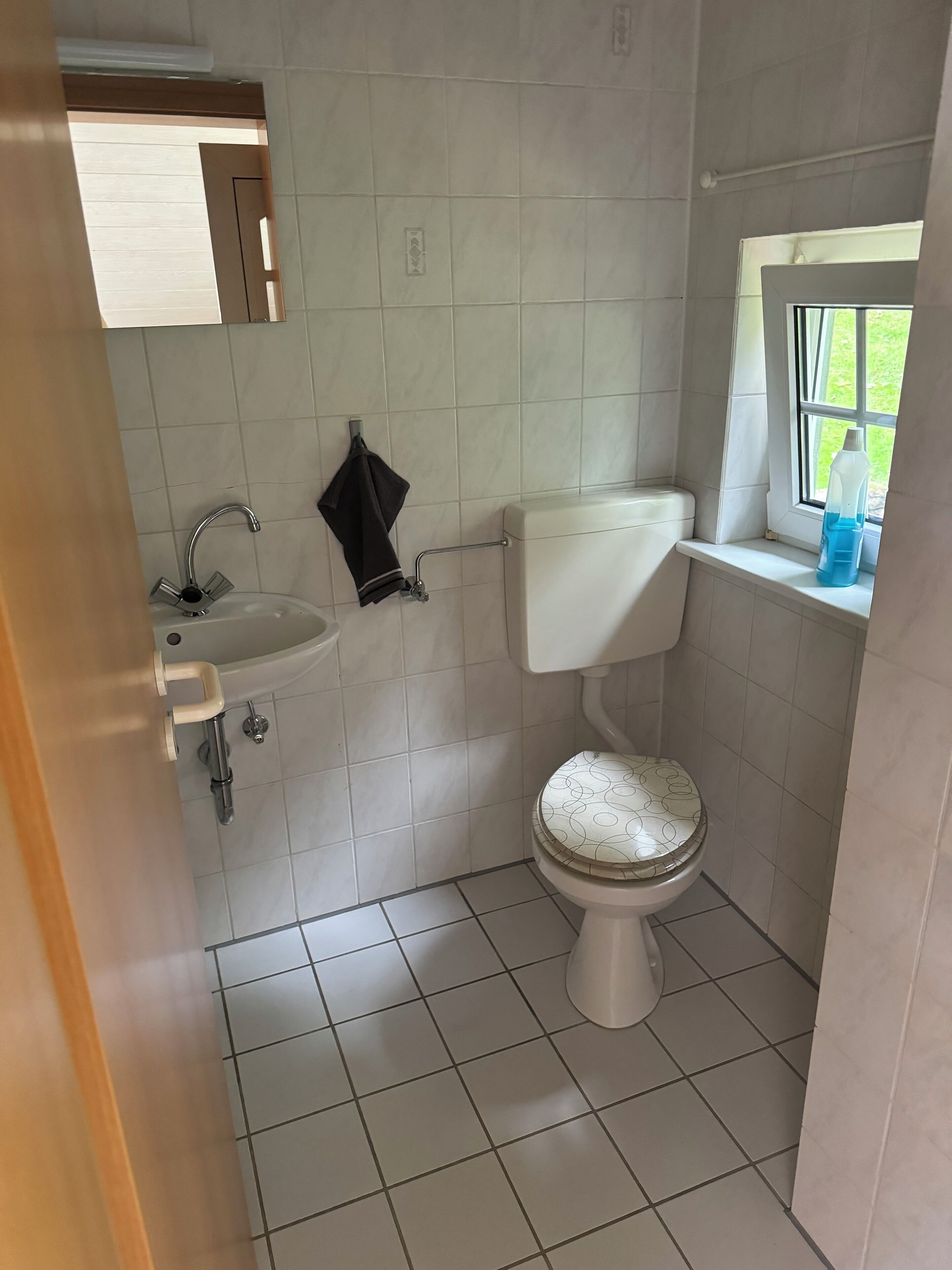 A small bathroom with a toilet, sink, and window.
