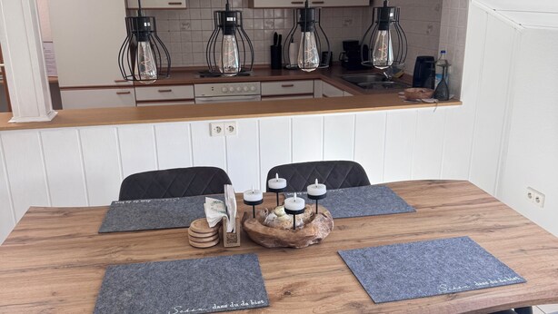 A dining area with a wooden table, four grey chairs, and a central decorative piece.