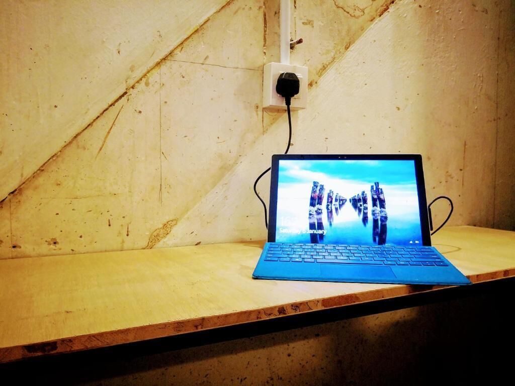 A laptop on a wooden table with a visible power outlet in the background.