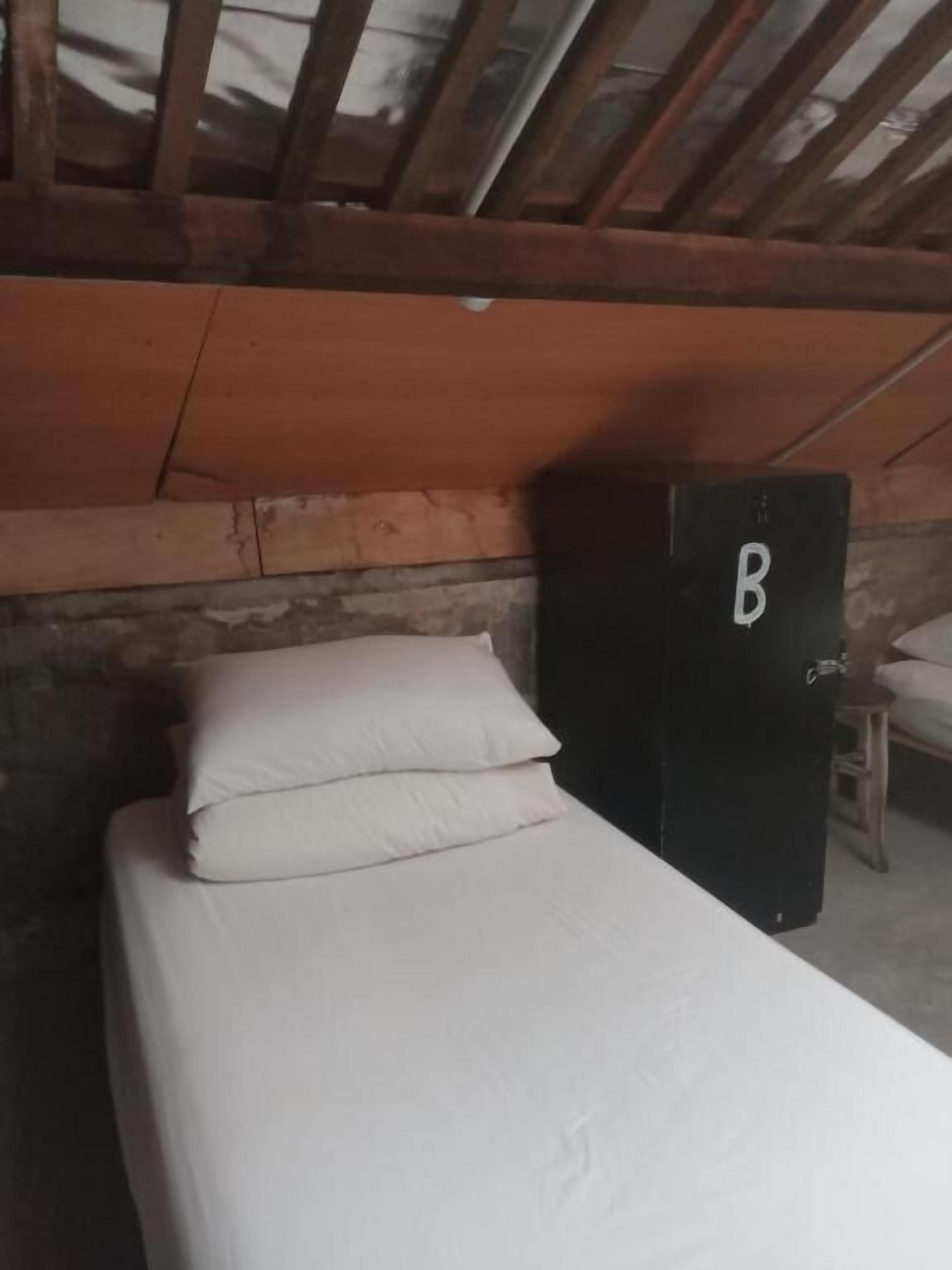 A single bed with white bedding in a room with wooden beams on the ceiling.
