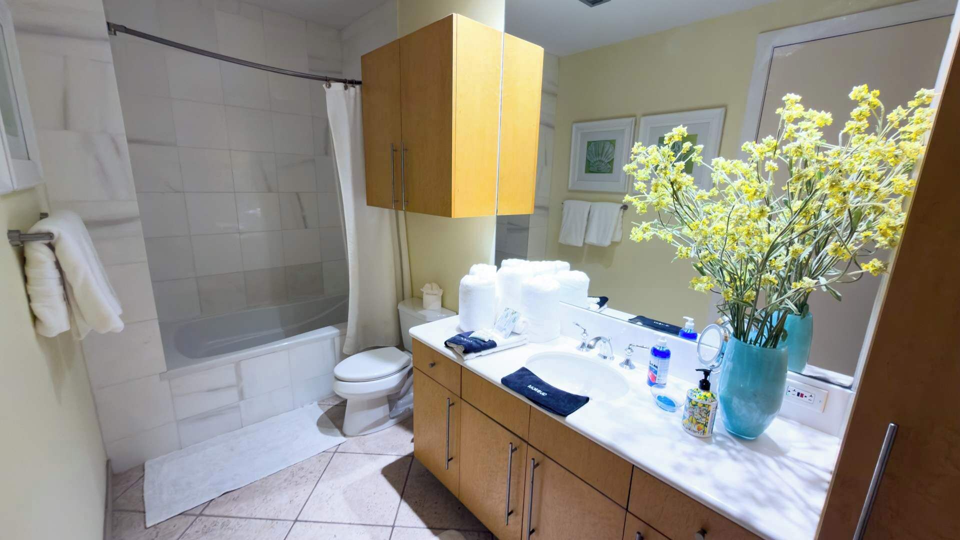 Un bagno con doccia, WC, lavandino e specchio. Asciugamani e articoli da toilette sono presenti sul ripiano.