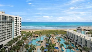 Un resort con zona de piscina, vista a la playa y varias edificaciones.
