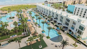 Un resort con varias piscinas, palmeras y vistas a la playa.