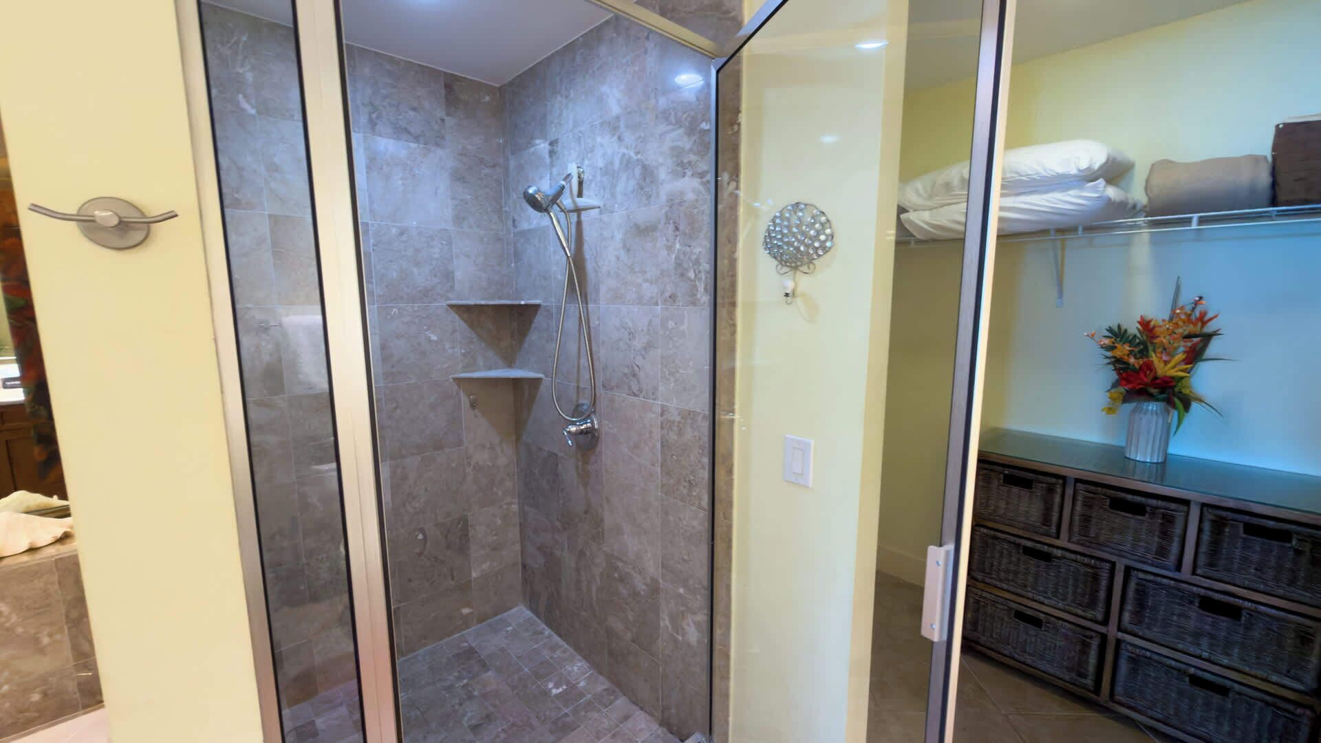 A glass-enclosed shower with a handheld showerhead and a wall-mounted faucet.