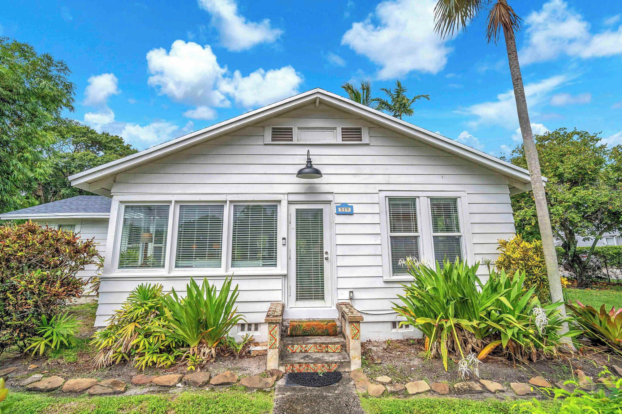 A white single-story house with a front porch, a mailbox, and a number sign.