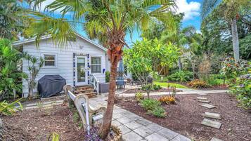 A house with a garden, a covered patio, and a pathway leading to the front door.