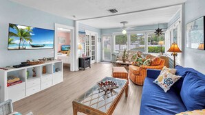 Un salón amplio con televisor grande, asientos cómodos y vistas al exterior.