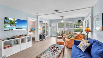 A spacious living room with a large TV, comfortable seating, and a view of the outdoors.