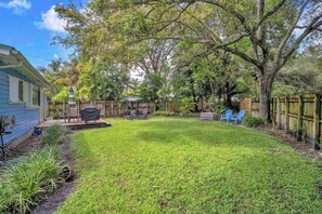 A backyard with a lawn, a wooden deck, and a house.