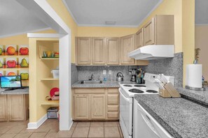 A kitchen with wooden cabinets, a granite countertop, a stove, and a sink.