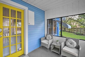 A covered porch with a yellow door, blue walls, and wicker furniture. - Blue Reverie - Near Las Olas (Fort Lauderdale)
