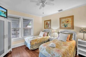 A bedroom with two beds, a television, and artwork on the walls.