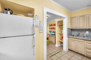 A compact kitchen with a white refrigerator, wooden cabinets, and a granite countertop.