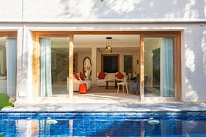 Una sala de estar moderna con vista a la piscina, que incluye un sofá, una mesa de centro y un comedor.