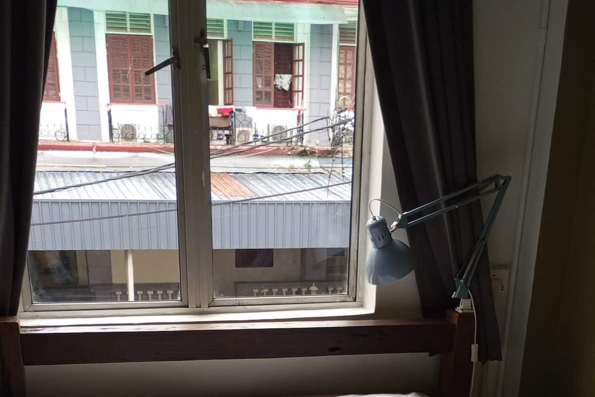 Un llit amb roba de llit blanca i dos almoinos, una tovallola fosca i una finestra amb cortines.