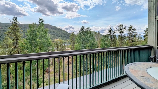 A balcony with a view of a forested mountain range and a clear sky.