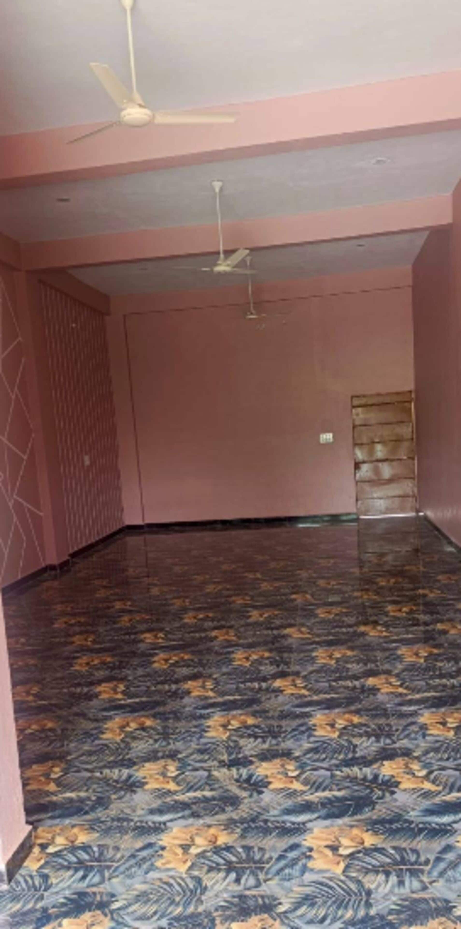 A room with a patterned floor, a ceiling fan, and a door.