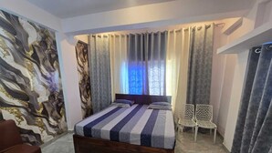A bedroom with a large bed, a chair, and a decorative wall.
