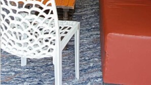 A corridor with a reception desk, a wooden table, a white chair, and a red sofa.