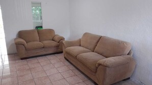 A room with two beige sofas and tiled flooring.