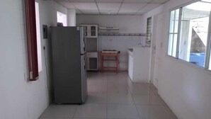 A kitchen with a refrigerator, a wooden table, and cabinets.
