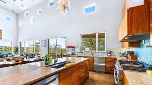 A spacious kitchen with a large island, stainless steel appliances, and a view of the outdoors.