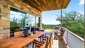 A wooden dining table with chairs, a stone wall, and a view of the landscape.