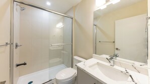 Uma casa de banho moderna com cabine de duche em vidro, sanita branca e lavatório de mármore.