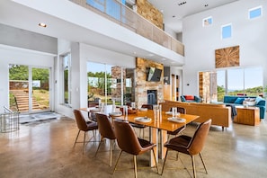 A spacious interior with a dining area, a fireplace, and a balcony overlooking greenery.