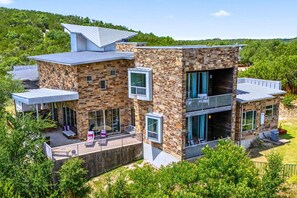Uma casa moderna de dois andares com fachada de pedra, janelas amplas e uma varanda.
