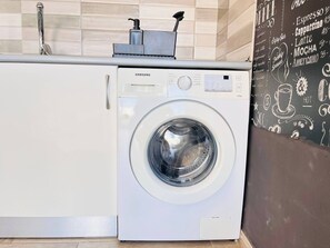 A Samsung washing machine in a kitchen with a tiled backsplash and a chalkboard menu listing coffee and food items. - Lovely Ocean House by Alquiler de Sueno (Mogan)