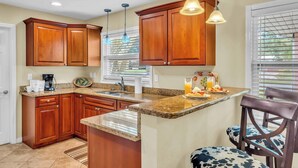 A kitchen with wooden cabinets, granite countertops, and pendant lighting. - Gulf Gate Dream 2bd 2ba Htd Pool Beaches Shopping (Sarasota)