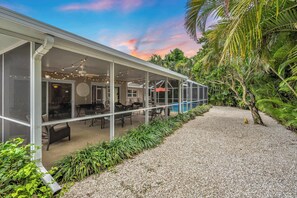 Une maison moderne dotée d’un patio couvert, d’un espace salon extérieur et d’une piscine.